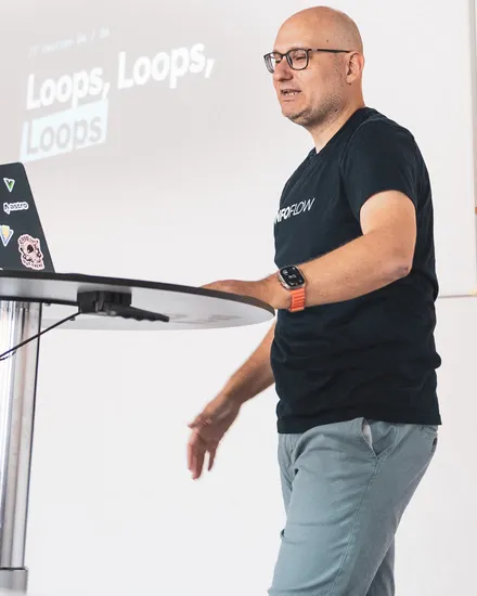 Florian mid-talk beside a slide reading “Loops, Loops, Loops”